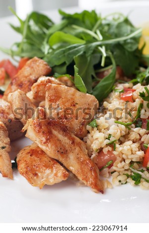 Grilled chicken meat with bulgur wheat and rocket salad