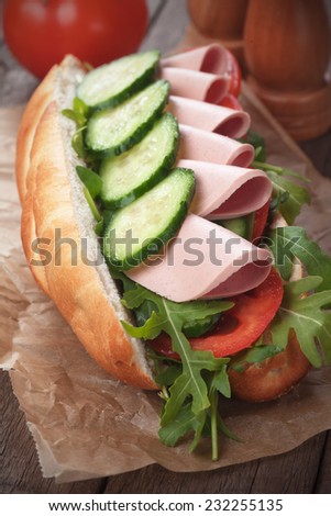 Submarine sandwich with salami, cucumber, tomato and rocket salad