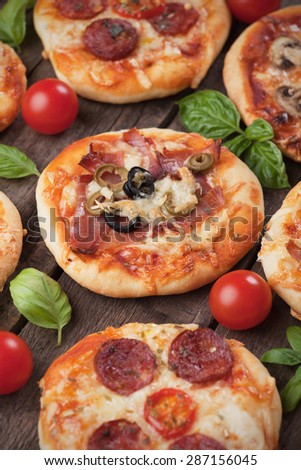 Mini pizzas with ham, salami, cheese and tomato