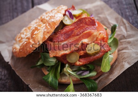 Sandwich with fried bacon, tomato and pickles