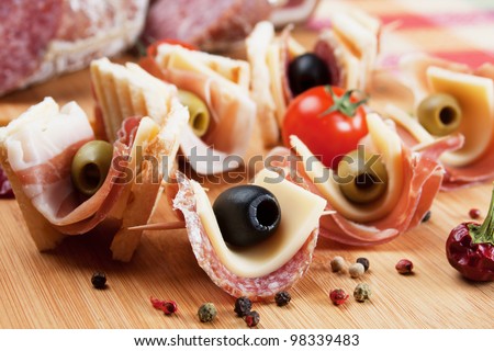Canape with pickled olives, salami and prosciutto