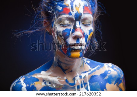 Beautiful face of a woman covered in paint Close up of a woman's face covered in blue, red and purple paint