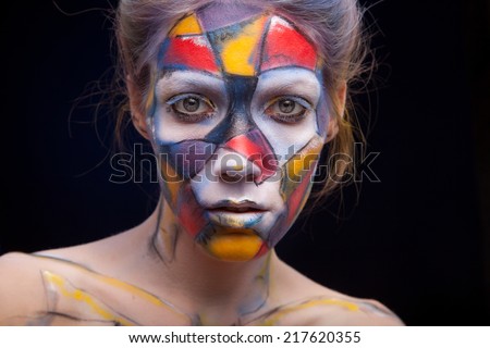 Beautiful face of a woman covered in paint Close up of a woman\'s face covered in blue, red and purple paint