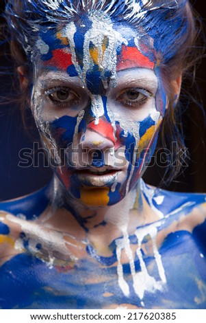 Beautiful face of a woman covered in paint Close up of a woman's face covered in blue, red and purple paint