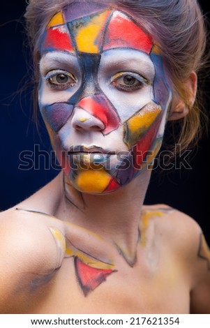 Portrait of a woman with face art.  who is posing covered with blue, red paint