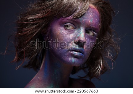 Beautiful face of a woman covered in glitter Close up of a woman\'s face covered in blue and purple glitter