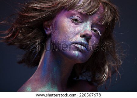 Beautiful face of a woman covered in glitter Close up of a woman\'s face covered in blue and purple glitter