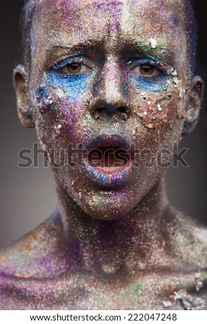 Beautiful face of a woman with face art and covered in glitter Close up of a woman\'s face covered in blue and purple glitter