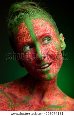 emotional woman with red multi lines and green hair. red flowers face art and body paint
