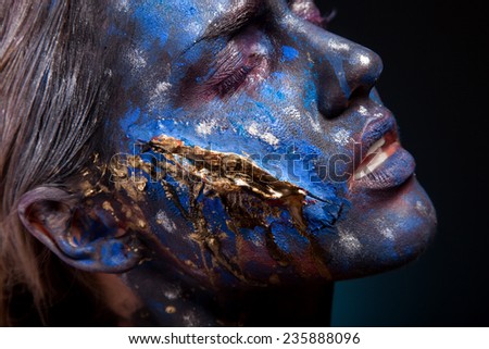 Blue face art woman with gold scar on face. Girl painted on blue color. Portrait
