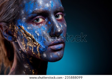 Blue face art woman with gold scar on face. Girl painted on blue color. Portrait