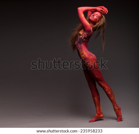 Sport woman in red posing in studio. With body art and face art. Painted body. Yoga. Fit woman doing stretching exercises