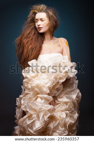 Woman in wedding dress. Young attractive and smiling Bride posing in studio. Luxury dress. Creative face art on face.  Curly hair.