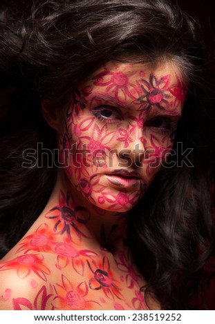 Pretty woman with flowers face art. Red flowers on face. Brunette hair. Face art and body art.