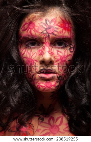 Pretty woman with flowers face art. Red flowers on face. Brunette hair. Face art and body art.