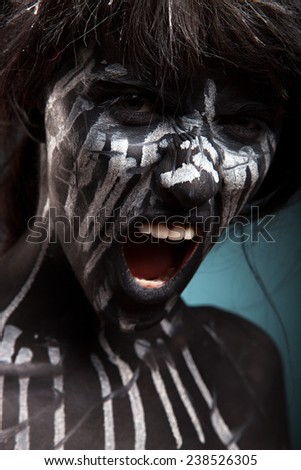 Girl with black face-art. White paint flow on face. Portrait of pretty woman on grey background. Face art and body-art.