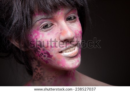 Pretty smiling woman with pink body art and face art. Paint on face. Cool make-up