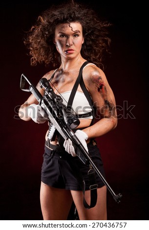Sexy military woman posing with sniper gun. With blood, dirty face and wound.