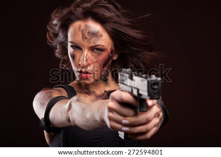 Sexy woman with military, riot uniform in studio on dark red background. With gun and blood drop on face.