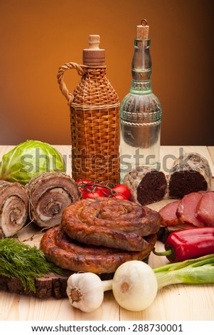 Smoked meat raw bacon and sausages with vegetables and salad with bottles of alchohol vodka and wine