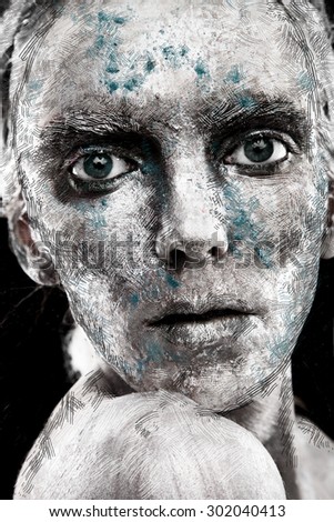 Portrait of a young mysterious alien woman with big eyes and silver pigment over the face on dark background in studio