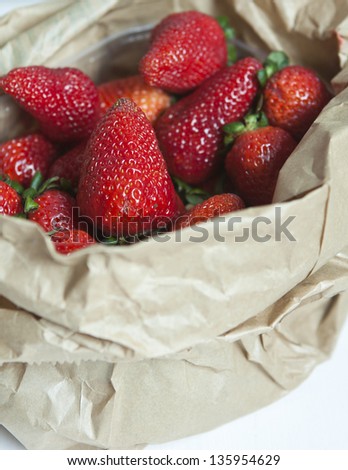 Paper bag full of ripe strawberries.