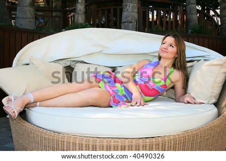 Pretty blonde girl lying on outdoor sofa.
