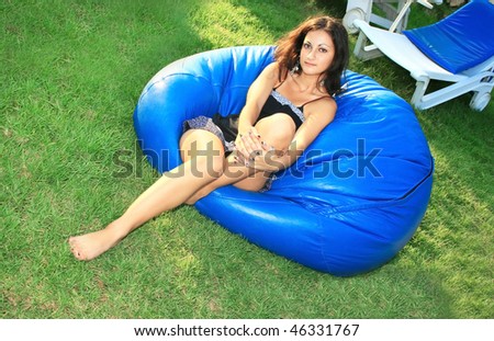 Pretty brunette girl on leather ball chair.