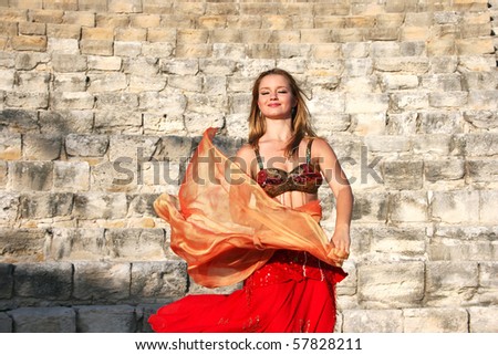 Beautiful belly dancer in red on the ancient stairs of Kourion amphitheatre in Cyprus.