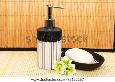 Soap dispensers and bar on bamboo background.