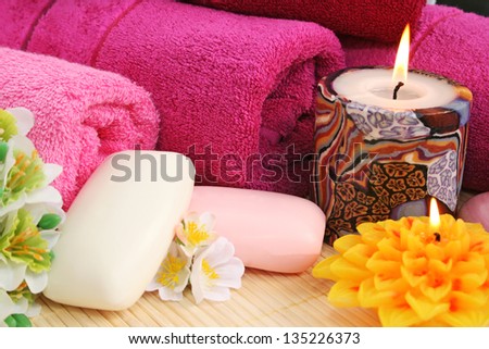 Towels, soaps, flowers and candles on mat background.