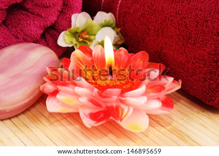 Towels, soap, flower and candle on mat background.