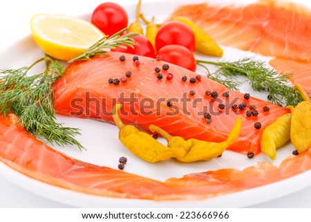 Salmon fillet with lemon, dill, pepper, tomatoes on plate.