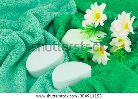 Green towels, flowers and soaps closeup picture.
