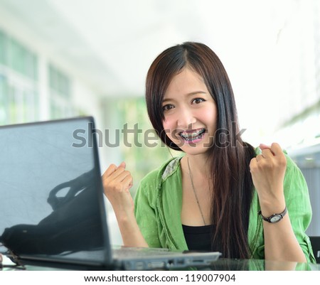 Beautiful young student have good news on the computer screen