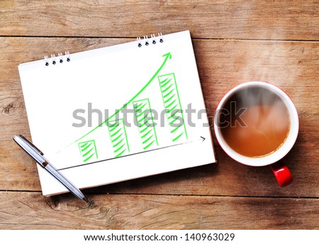Hot coffee cup with growing green graph paper on wood background