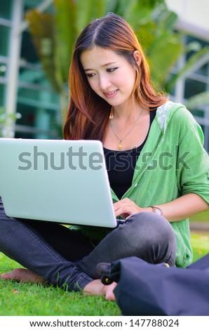 Beautiful young asian student smiling with computer notebook at garden