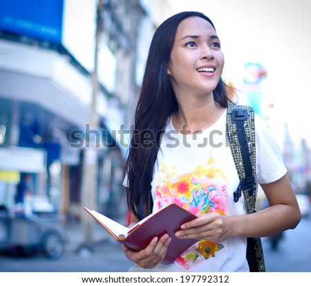 Asian woman traveling in Thailand with map and guide book