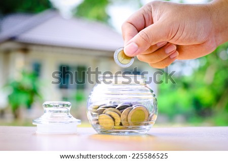 Male hand putting money coins with home, Saving for buy home concept