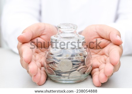 Insurance concept,Male hand protected money coins in glass jar bank