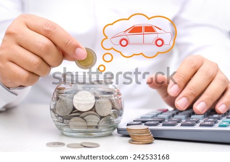 businessman hand putting money coins into glass piggy bank for buy car
