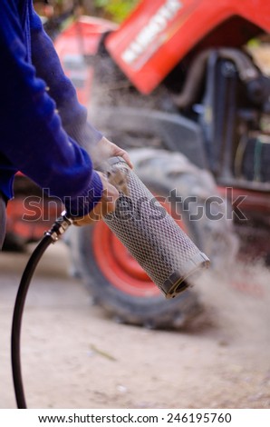 Farmer is cleaning pushcart engine air filter by air pump