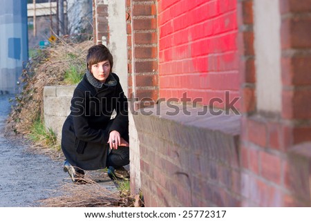 A woman kneels down and looks at the camera for an original portrait.