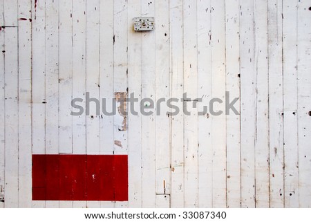 A white wall with vertical lines cracking in the paint and a red rectangle at the bottom left.  Ideal for a design layout of a simple sort with plenty of copy space and room for text.
