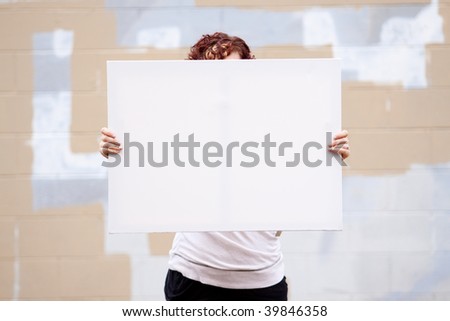 An anonymous girl holds a large white canvas sign with room for text or copy space.