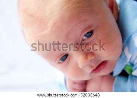 A very young baby boy child is photographed while he is 0-3 months old infant.
