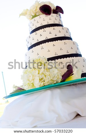 Wedding cake detail at a marriage ceremony and reception. The cake is white with black and has flowers on it and frosting.