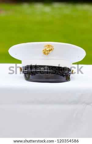A marines hat off his head while at a wedding in uniform for armed forces soldiers and family.
