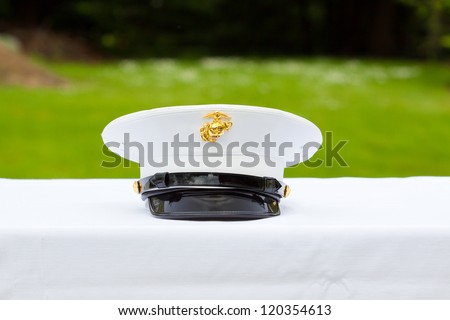 A marines hat off his head while at a wedding in uniform for armed forces soldiers and family.