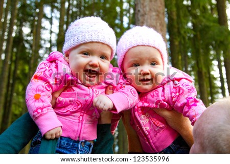 These two twin girls are having a fun time playing with their parents as they are lifted high in the air.
